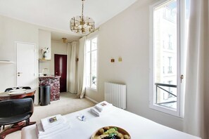 Hotelkamer met een bed, een eettafel met stoelen, een kroonluchter, uitzicht en een radiator.