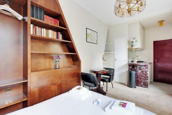 Une chambre d’hôtel avec une bibliothèque en bois, un bureau avec une chaise, un lit avec des serviettes et un comptoir en marbre.