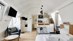 Une chambre d’hôtel moderne équipée d’un lit, d’un bureau, d’une chaise, d’une télévision, d’un coin cuisine et d’une salle de bain.