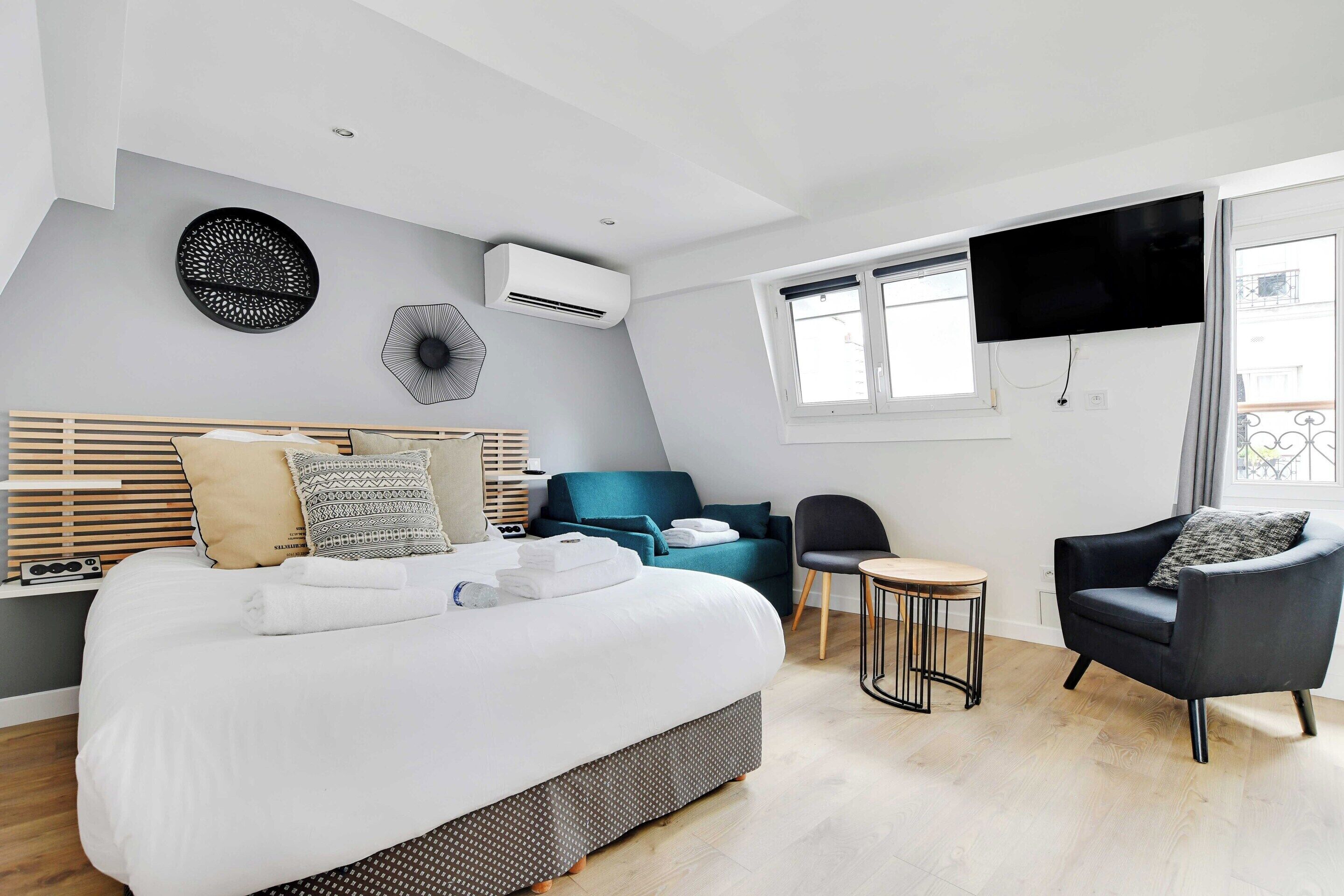 Ein modernes Hotelzimmer mit einem großen Bett, einem Fernseher, einem kleinen Tisch und einer Couch.