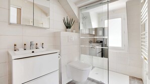 Une salle de bain moderne avec un lavabo blanc, un miroir et des toilettes.