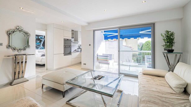 A modern living room with a glass coffee table, a sofa, and a large sliding glass door leading to a balcony. - Beautiful 2P Apartment With Sunny Terrace (Cannes)