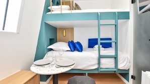 A bunk bed room with a table set for two, a wooden desk, and a small stool. - Cosy Studio - 2P - Strasbourg Saint-denis (Paris)