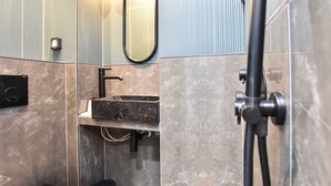 A bathroom with a marble sink, a mirror, and a shower. - Cosy Studio - 2P - Strasbourg Saint-denis (Paris)