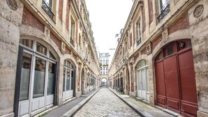 A cobblestone street flanked by historic buildings with arched windows and doors, leading to a central archway. - Cosy Studio - 2P - Strasbourg Saint-denis (Paris)
