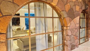 Ein Zimmer mit Steinwänden, einem großen Bogenfenster, einem Kamin und einem Essbereich mit weißer Möbel.