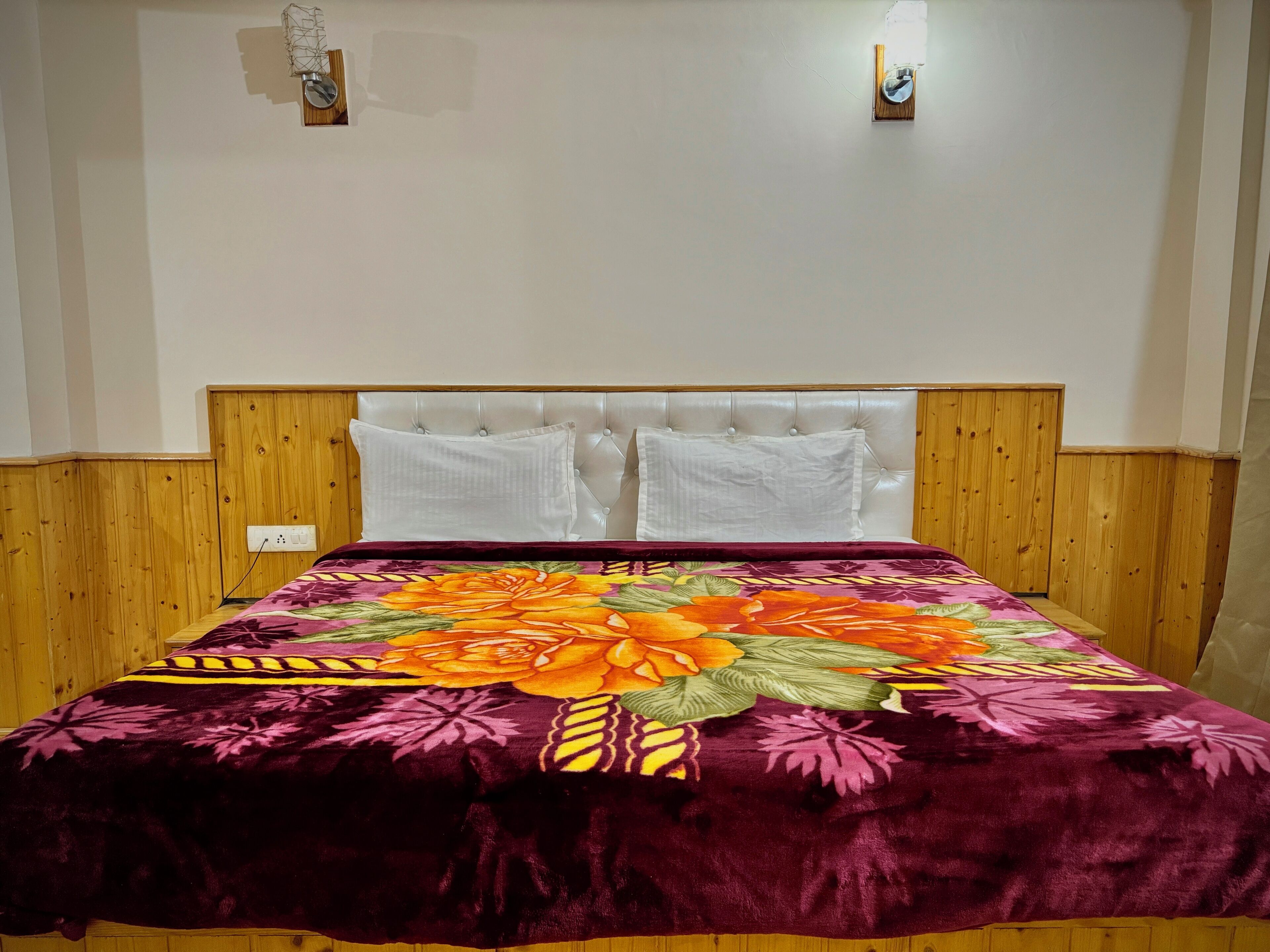 A bed with a floral bedspread, a wooden headboard, and two white pillows.