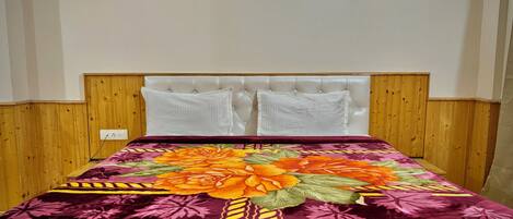 A bed with a floral bedspread, a wooden headboard, and two white pillows.