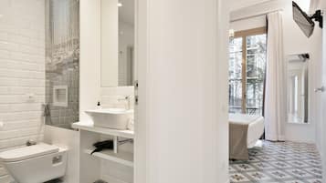 A modern bathroom with a freestanding bathtub, a vanity with a mirror, and a shower area.