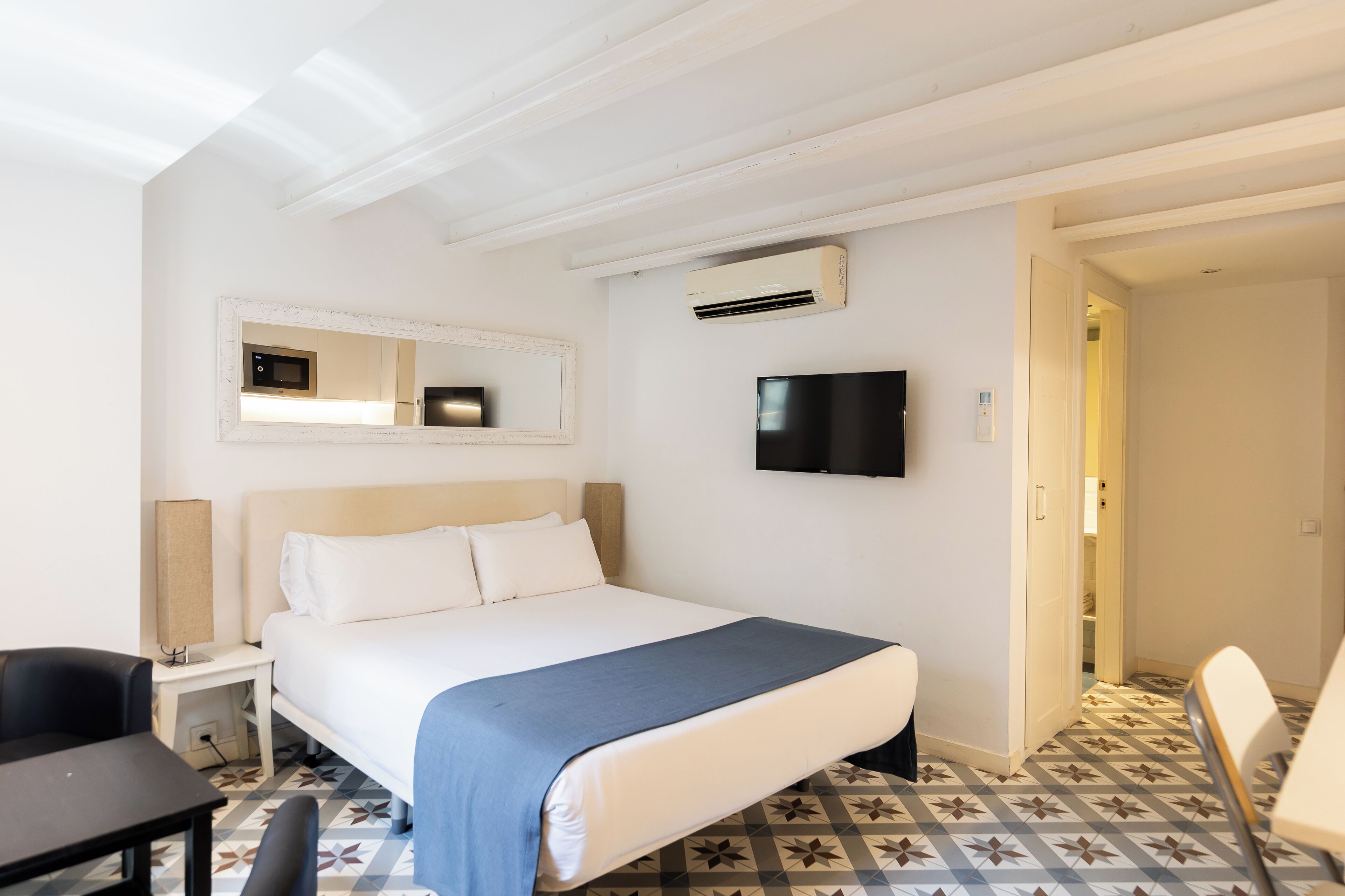 Una habitación de hotel con cama, televisor, escritorio y silla.