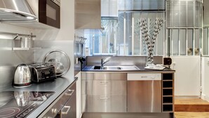 Eine moderne Küche mit Edelstahlgeräten, einem Geschirrspüler und einem Fenster mit Jalousien.