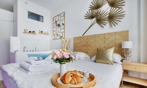 A modern bedroom with a bed, bedside table, lamp, and decorative wall art.