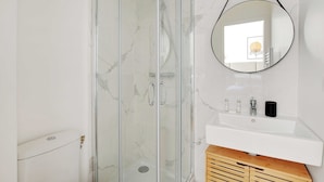 A bathroom with a glass shower enclosure, a white sink, and a round mirror. - Comfortable Studio - 2P - Clignancourt/sacre-coeur (Paris)