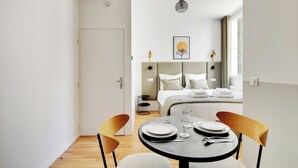A modern hotel room with a dining area, a bed with a view, and a minimalist decor. - Comfortable Studio - 2P - Clignancourt/sacre-coeur (Paris)