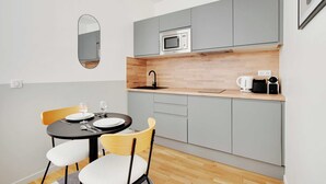 A compact kitchen with grey cabinets, a microwave, a coffee maker, and a round dining table with chairs. - Comfortable Studio - 2P - Clignancourt/sacre-coeur (Paris)
