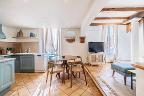 Eine kleine Küche mit Essbereich, einem Fernseher und einem fenster mit Vorhängen.