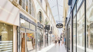 A covered shopping corridor with glass storefronts and a central passageway. - Apartment in Paris for 2 People (Paris)