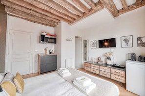 Ein Schlafzimmer mit Bett, Kommode, Spiegel und Fernseher an der Wand.