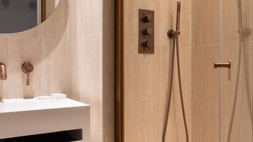 Une salle de bain moderne avec un lavabo blanc, un miroir rond et une douche séparée par des parois en verre.