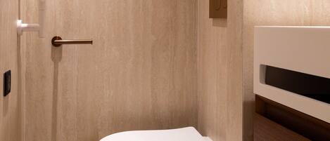 A modern bathroom with a toilet, a towel rack, and a wooden vanity.