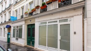 A building with a green door, white shutters, and a blue sign. - Love Room - 2P With Jacuzzi (Paris)