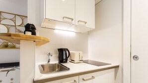 A compact kitchenette with a stainless steel sink, a coffee maker, and a toaster. - Love Room - 2P With Jacuzzi (Paris)