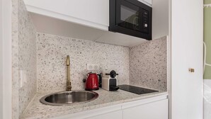 Eine Küche mit Granit-Arbeitsplatte, Spüle aus Edelstahl, einem roten Wasserkocher, einer Kaffeemaschine und einer schwarzen Mikrowelle.