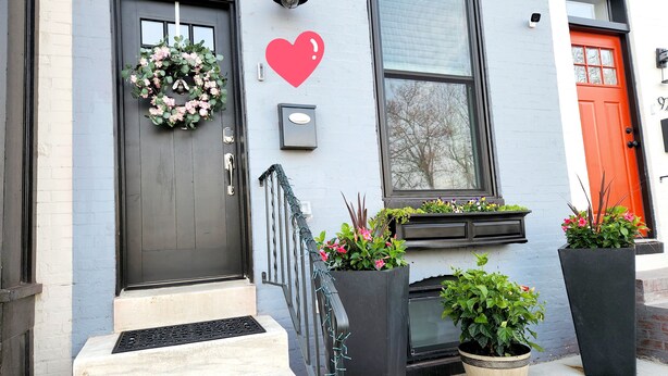 Un bâtiment avec une porte sombre, un décor en forme de cœur et des plantes en pot.