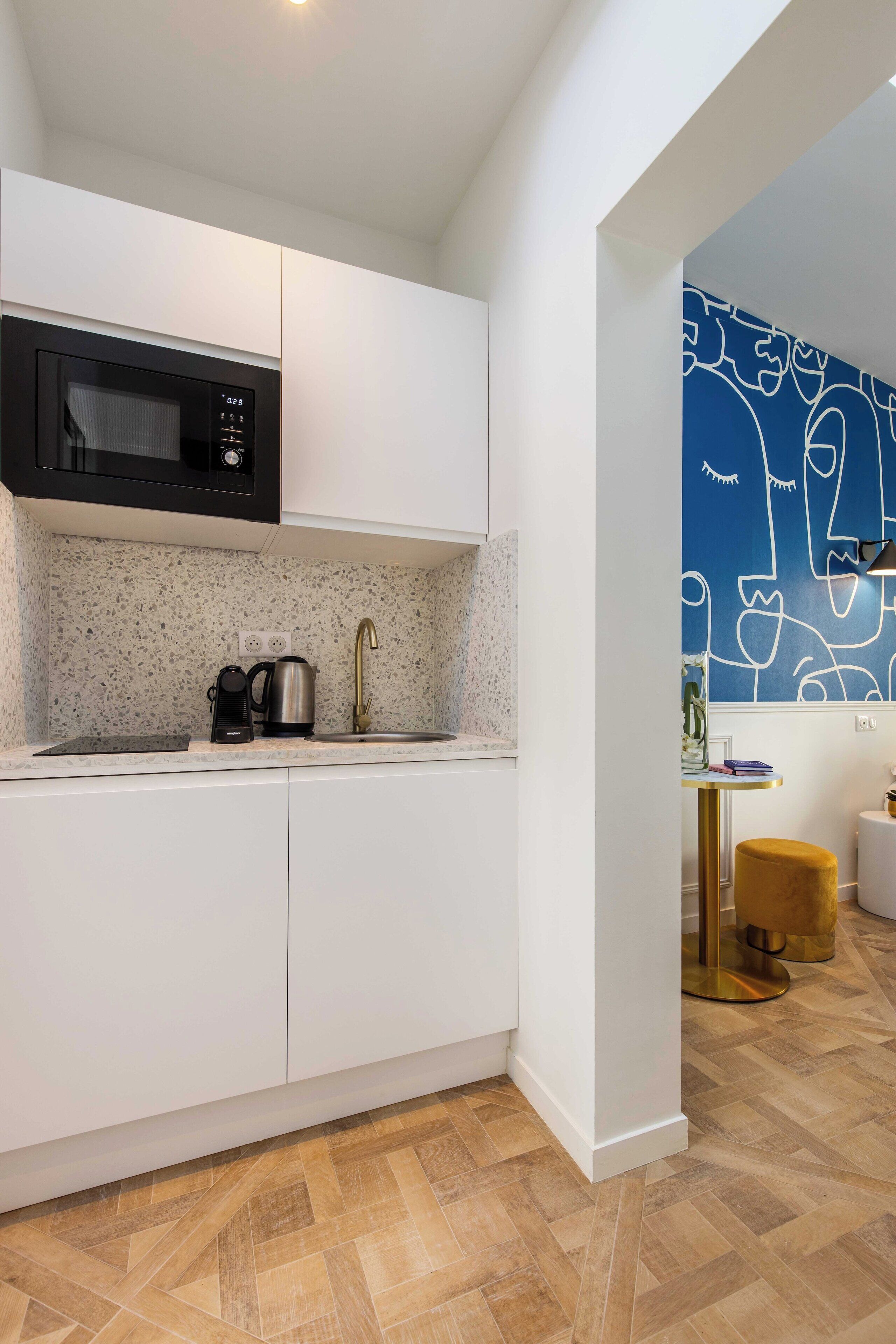 A modern kitchen with white cabinetry, a microwave, a coffee maker, and a sink. - Charming Studio - 2P - Pigalle/sacre-coeur (Paris)