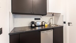 Una cocina compacta con encimera negra, cafetera, tostadora y hervidor.