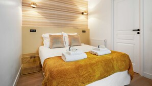 Ein Hotelzimmer mit Bett, einer Kopfteilbeleuchtung, einer Tür und einem Heizkörper.
