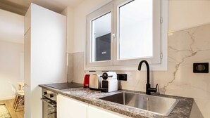 Eine moderne Küche mit Einbauofen, Edelstahlspüle und Fenster über der Arbeitsplatte.