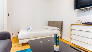 A modern hotel room with a bed, a desk, a television, and a cactus decoration. - Cozy Studio in the Heart of Paris (Paris)