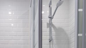 A glass-enclosed shower area with a handheld showerhead and a wall-mounted faucet. - Cozy Studio in the Heart of Paris (Paris)
