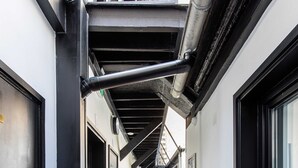 Ein schmaler Flur mit Holzboden, schwarzen Türrahmen und einer Treppe, die in ein Obergeschoss führt.