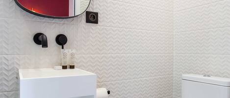 Een badkamer met een wit wastafel, een spiegel en een toilet.