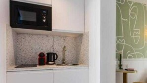 Une cuisine compacte équipée d’un four à micro-ondes, d’une machine à café et d’un évier.