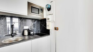Una cocina moderna con encimera de mármol negro, pileta de acero inoxidable y microondas integrado.