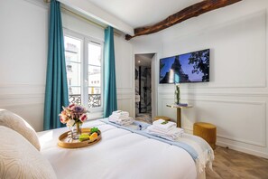 Ett hotellrum med en säng, ett litet träbord, en tv och utsikt över Eiffeltornet.