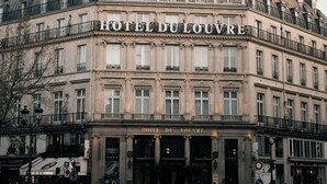 A historic building with the sign "HOTEL DU LOUVRE" indicating it is a hotel.