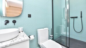 A modern bathroom with a glass shower enclosure, a white sink, and a mirror above the sink.