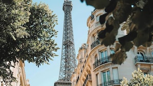A street view with the Eiffel Tower in the background, surrounded by historic buildings and trees. - Charming Studio - 2P- Javel/tour Eiffel (Paris)