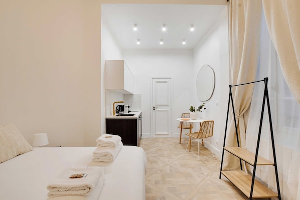 Una habitación de hotel con cama, kitchenette pequeña, zona de comedor y baño.