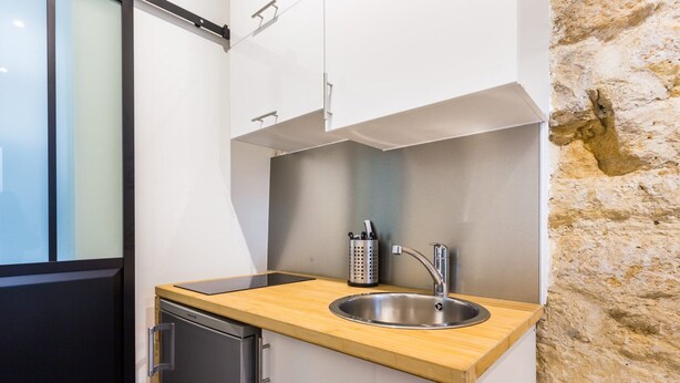 A compact kitchen with a wooden countertop, stainless steel sink, and a dishwasher.
