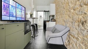 Egy modern konyha, nagy, lapos képernyős televízióval, bárszékes étkezővel és díszes, kőburkolatos falakkal.