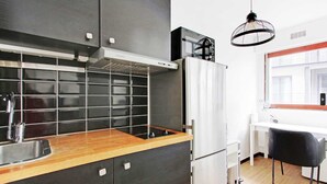 Una cucina moderna con pannello di protezione nero, elettrodomestici in acciaio inossidabile e piano di lavoro in legno.