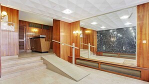 Una hall moderna di un hotel con pannelli in legno, una parete in marmo e una scala con ringhiera.