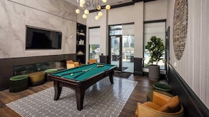 A modern indoor pool area with a pool table, comfortable seating, and a large window offering a view of the outdoors. - Cozy 10BR/BA combined Apartment Near DT Cincinnati (Cincinnati)