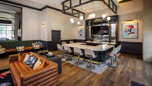 A modern interior with a curved staircase, a central island bar, seating areas, and artwork on the walls. - Cozy 10BR/BA combined Apartment Near DT Cincinnati (Cincinnati)