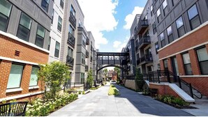 A multi-story residential building with a central pedestrian bridge, surrounded by greenery and a clear sky. - Cozy 10BR/BA combined Apartment Near DT Cincinnati (Cincinnati)
